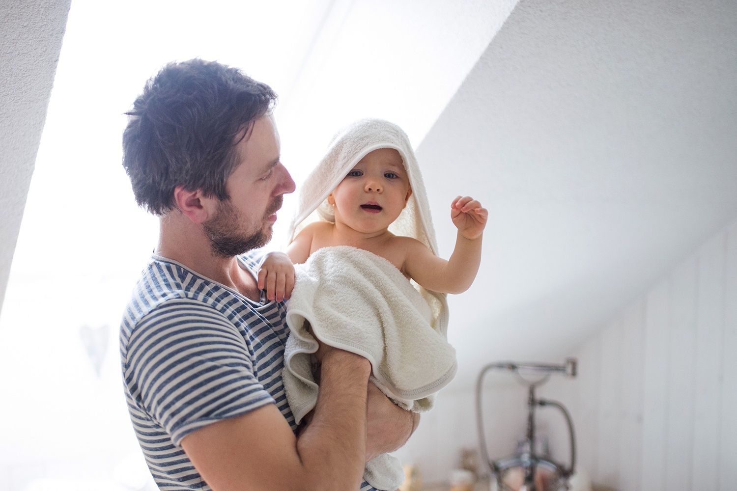 Vater hat sein in ein Handtuch gewickeltest Baby auf dem Arm