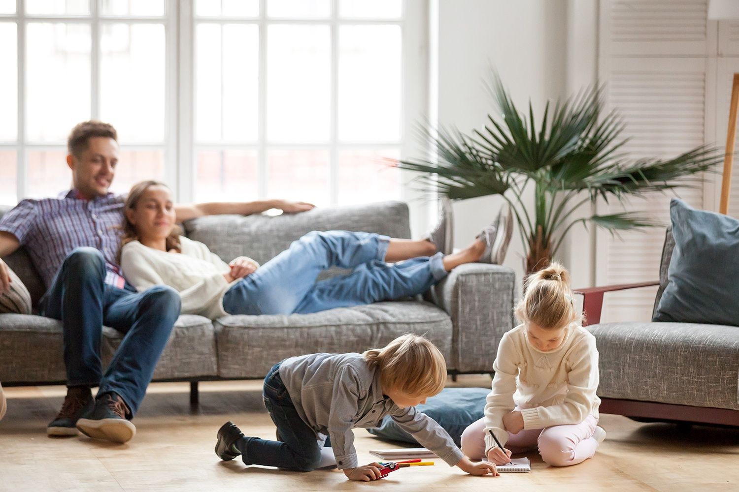 Mutter und Vater liegen entspannt auf der couch während die Kinder spielen